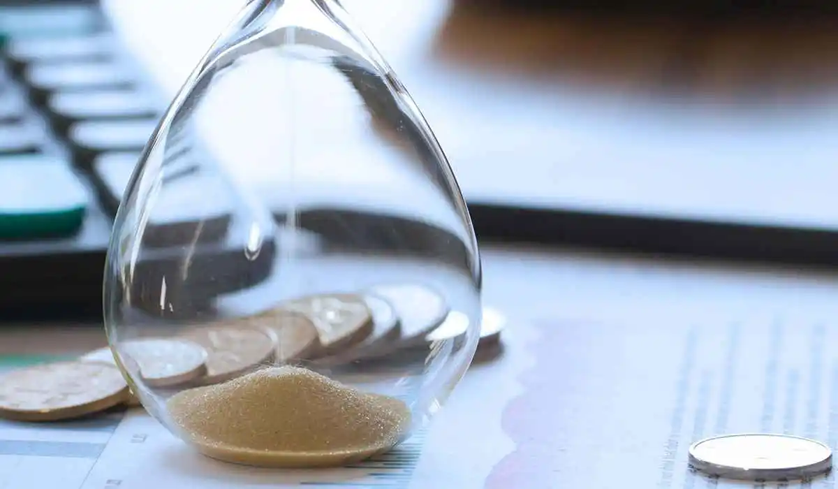 Hour Glass and dollar coins on a table