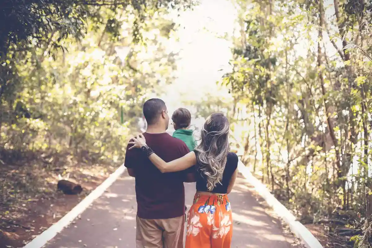 Family walking down a path through a forest.