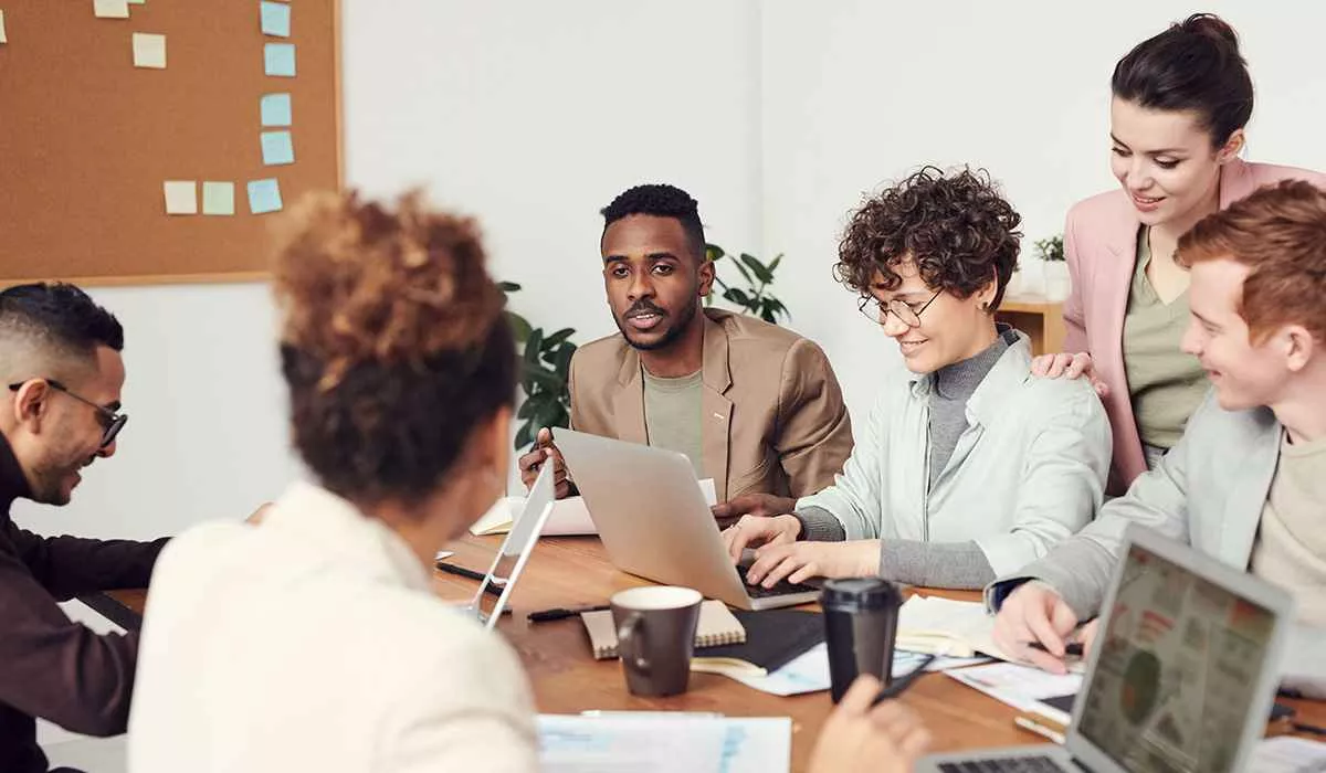 diverse group of people discussing and working around a wooden table with a office background 
