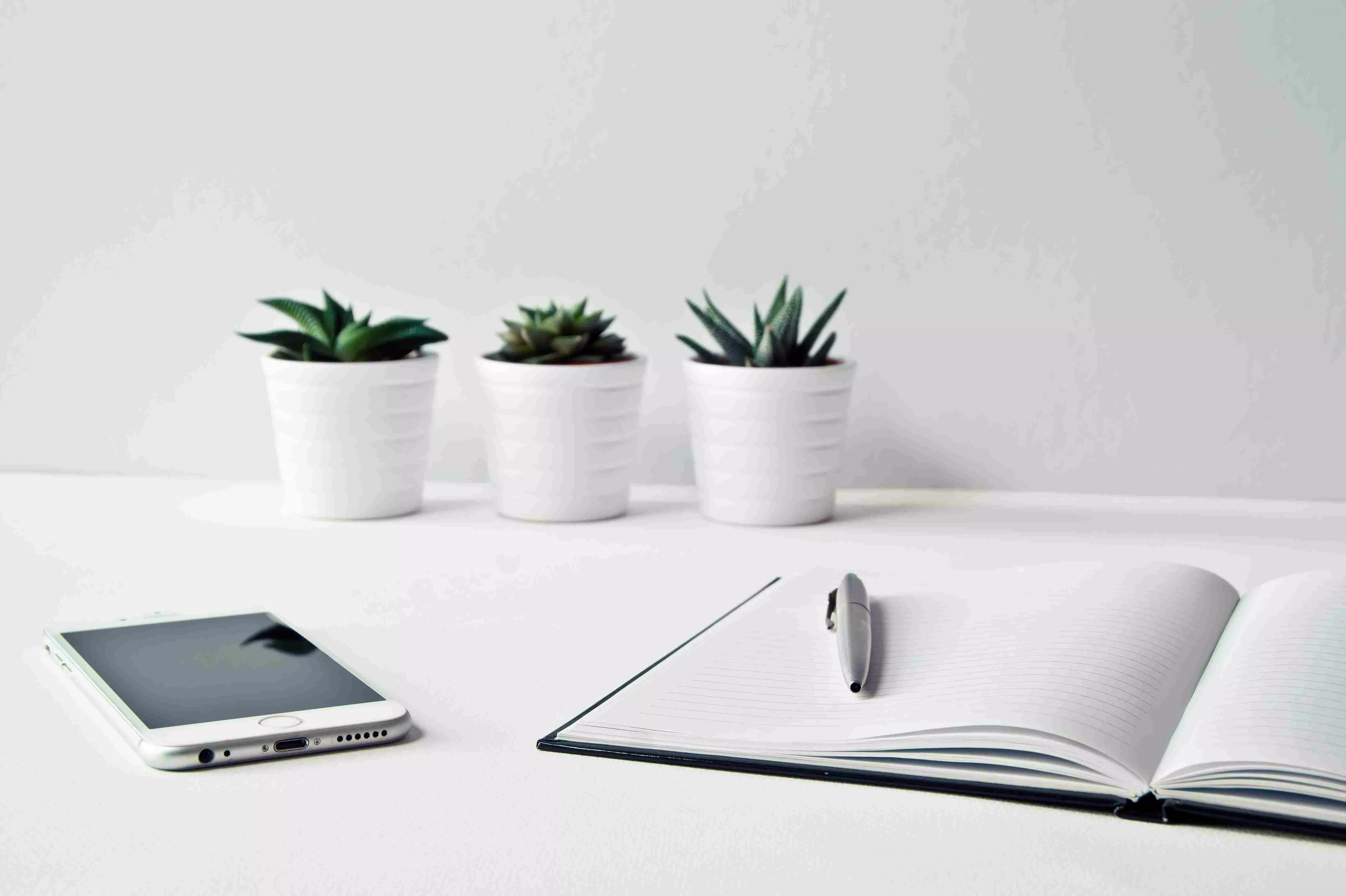 White Table with three pots, i-phone and notebook on it with white background
