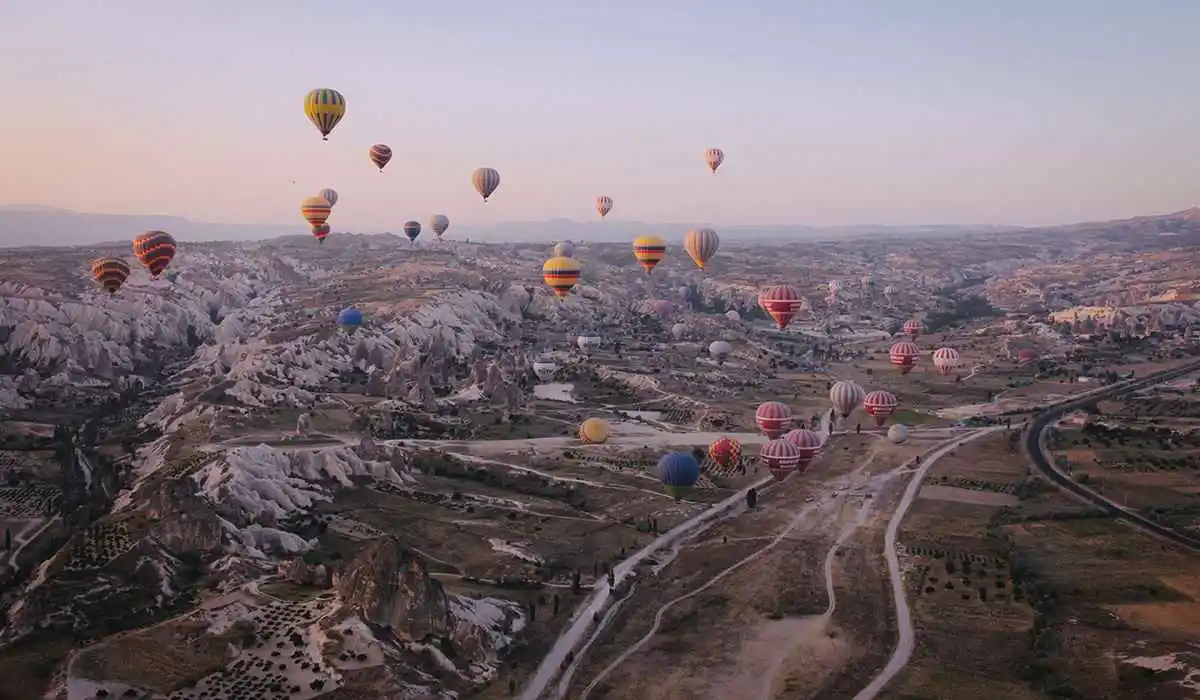 Hot Air balloons with hills in the background over a highway