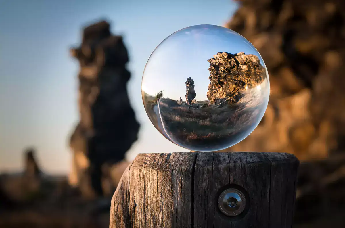 Rock formation reflected inside a glass sphere placed on a wooden surface, symbolizing perspective and clarity.